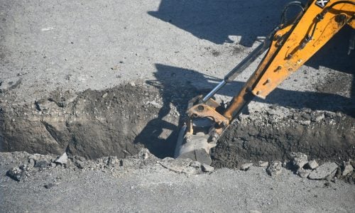 Photo by Anna Kharkivska Excavator digging a trench in the road